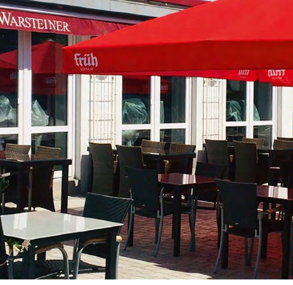 Das Hansecafé am Markt in Wipperfürth mit roten Sonnenschirmen vor dem Haus